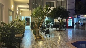 Ein Hotelinnenhof mit Sitzgelegenheiten im Freien, Palmen und einem Poolbereich.