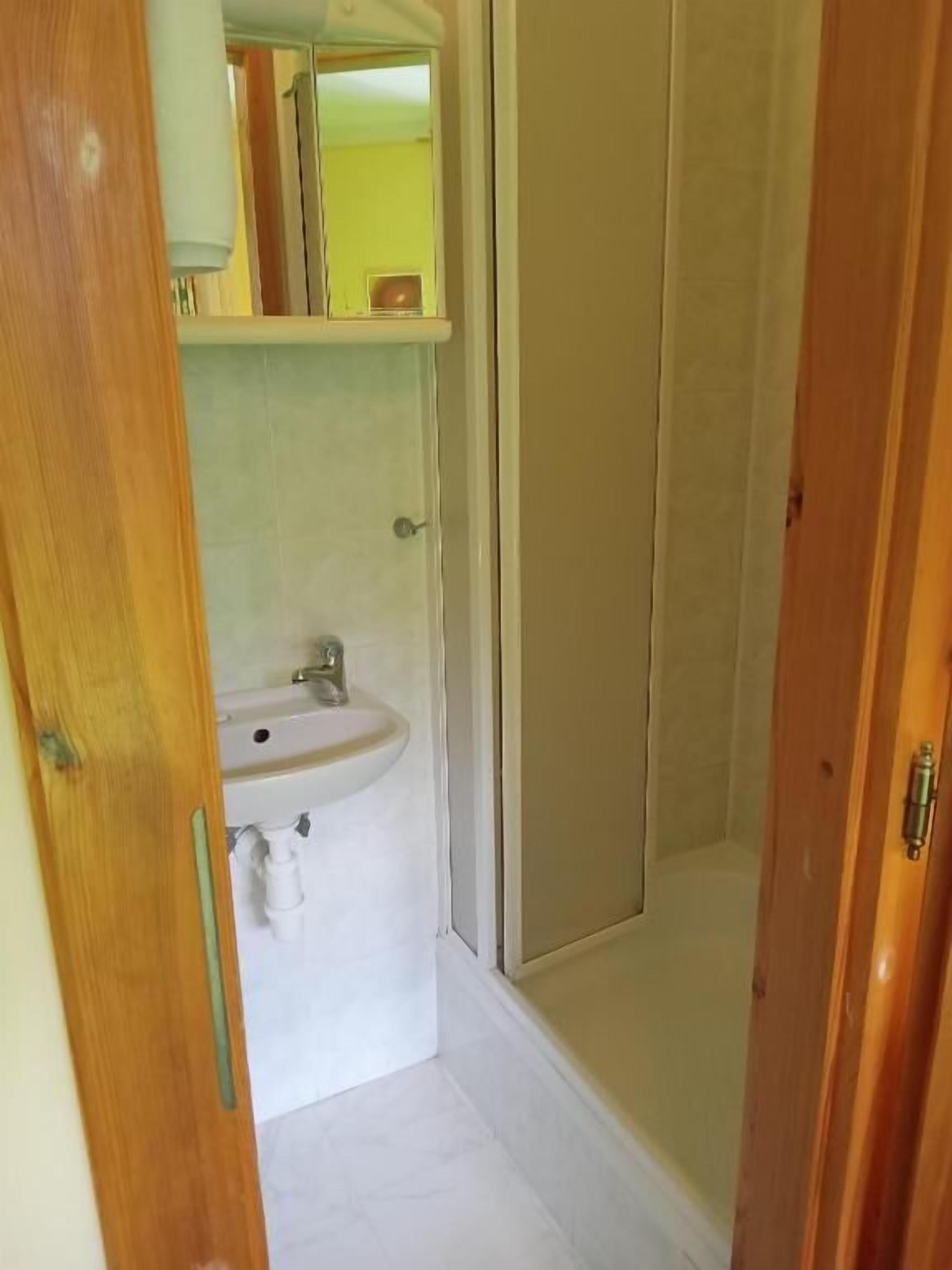 Un baño con lavamanos, espejo y cabina de ducha.