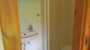 Un baño con lavamanos, espejo y cabina de ducha.