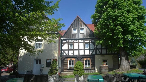 A traditional half-timbered building with a sign reading 'RESTAURACE' and outdoor seating. - U Zeleného stromu (Janov)
