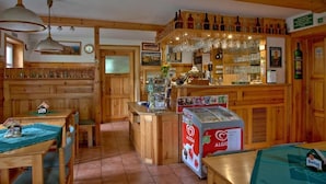 A wooden interior with a bar area, wooden furniture, and a refrigerator with a heart-shaped design. - U Zeleného stromu (Janov)