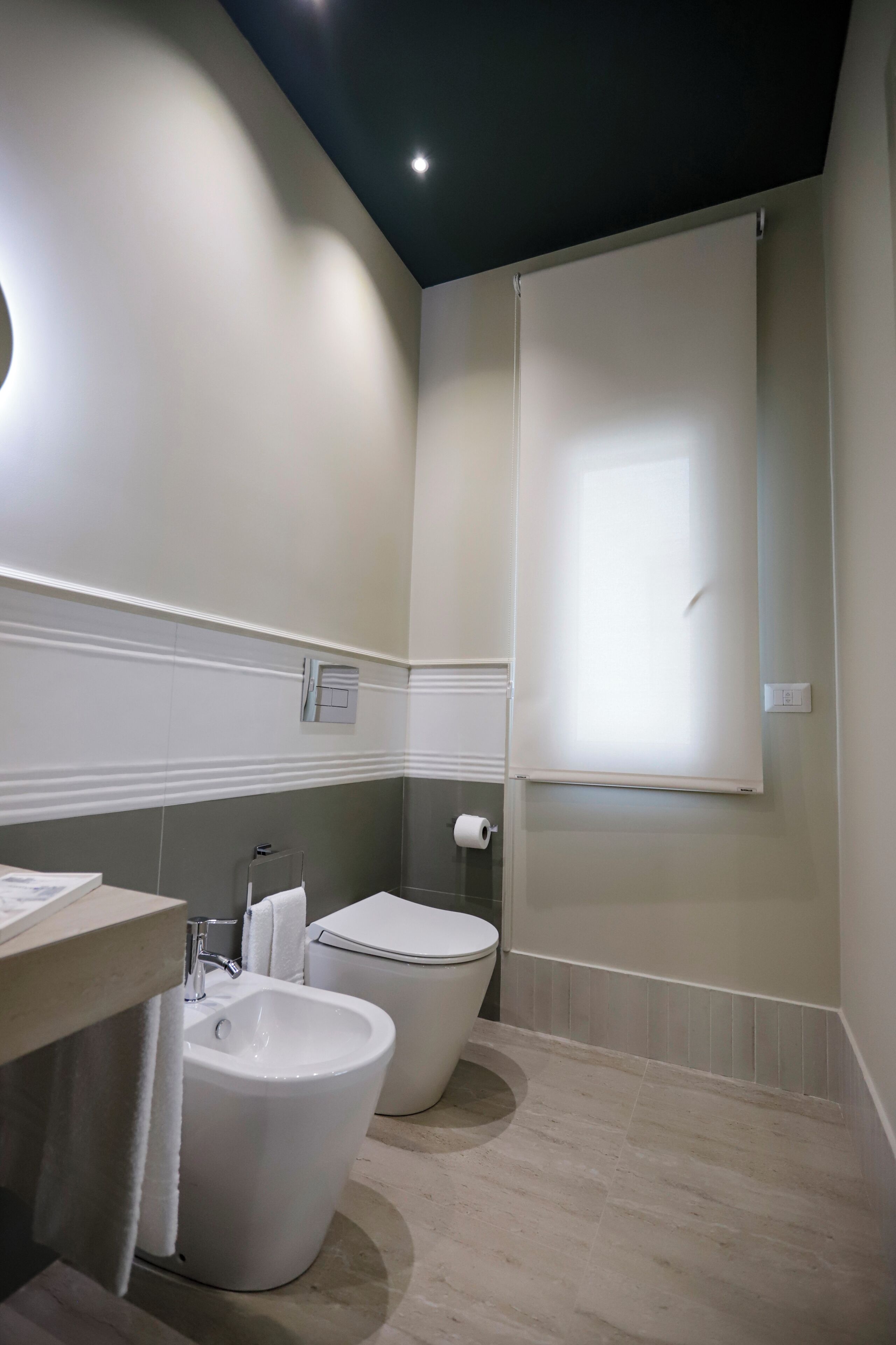 A modern bathroom with a bidet, toilet, and a large window.