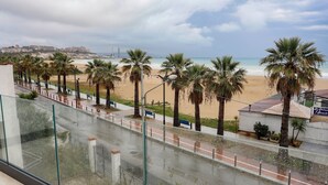 A beach view with palm trees, a pathway, and a building with a sign. - Seõra Luxury Rooms (Porto Empedocle)