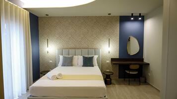 Quarto de hotel com uma cama, mesas de cabeceira, escrivaninha, cadeira e espelho.