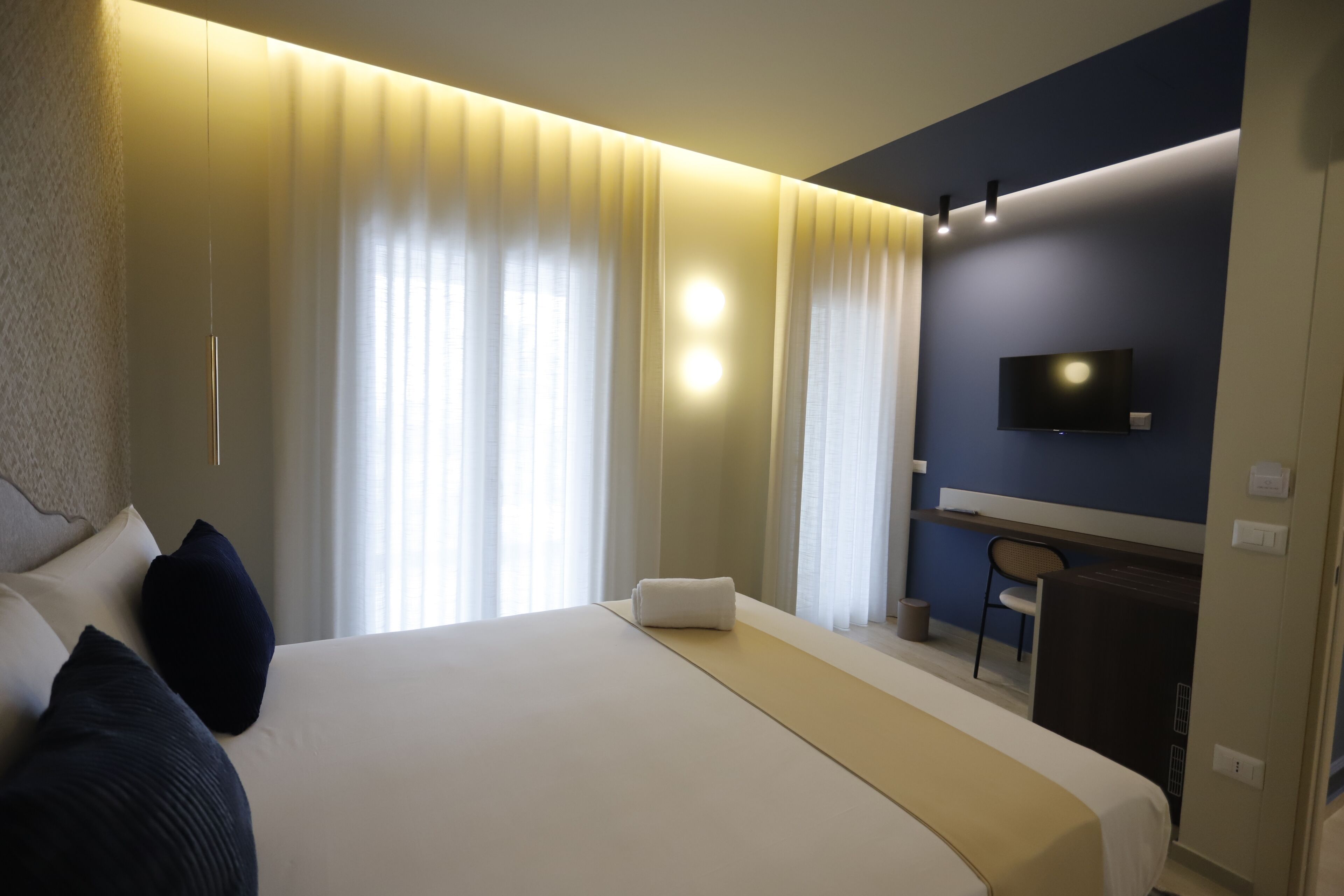 Hotelkamer met een groot bed, een bureau, een stoel, een flatscreen televisie aan de muur en een raam met gordijnen.