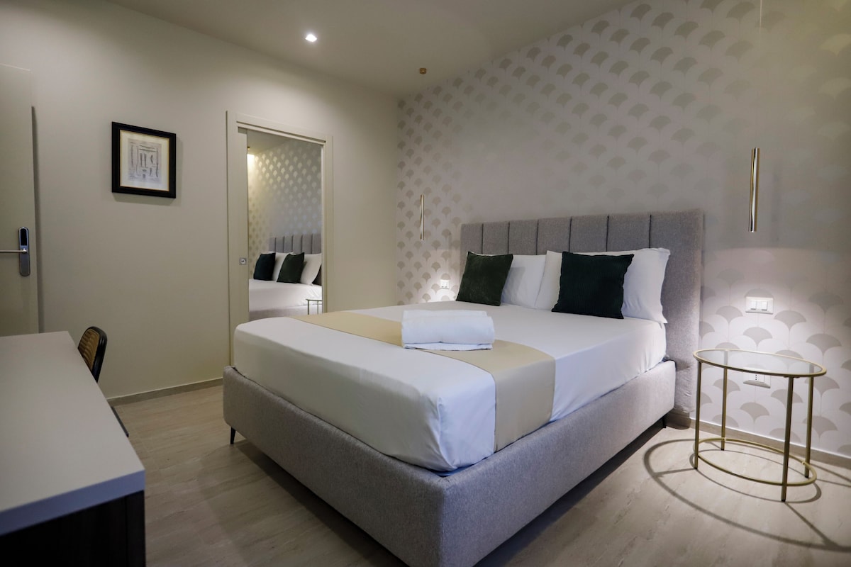 Habitación de hotel ordenada con cama, mesita de noche y escritorio.