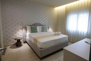 A neatly arranged hotel room with a bed, bedside table, and a small desk.