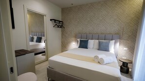 A modern hotel room with a large bed, a desk, and a chair. - Seõra Luxury Rooms (Porto Empedocle)