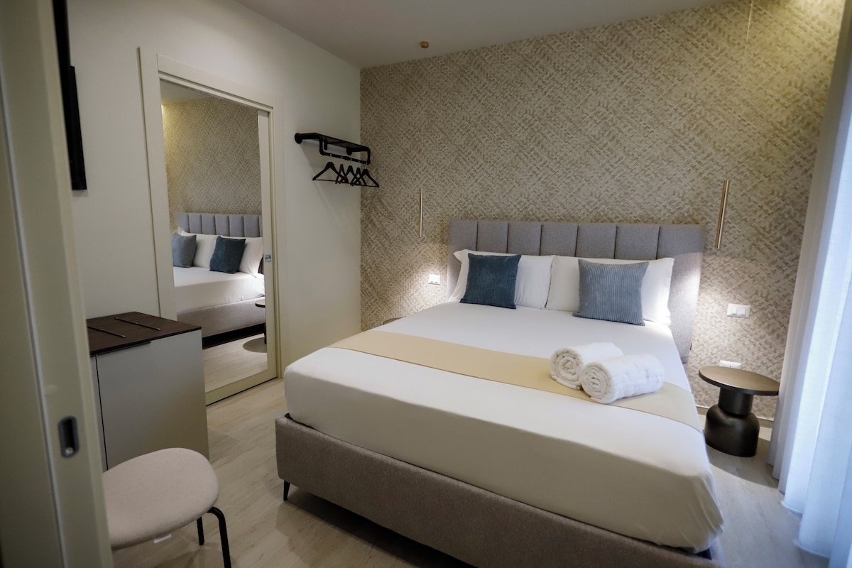 Una habitación de hotel moderna con una cama grande, un escritorio y una silla.
