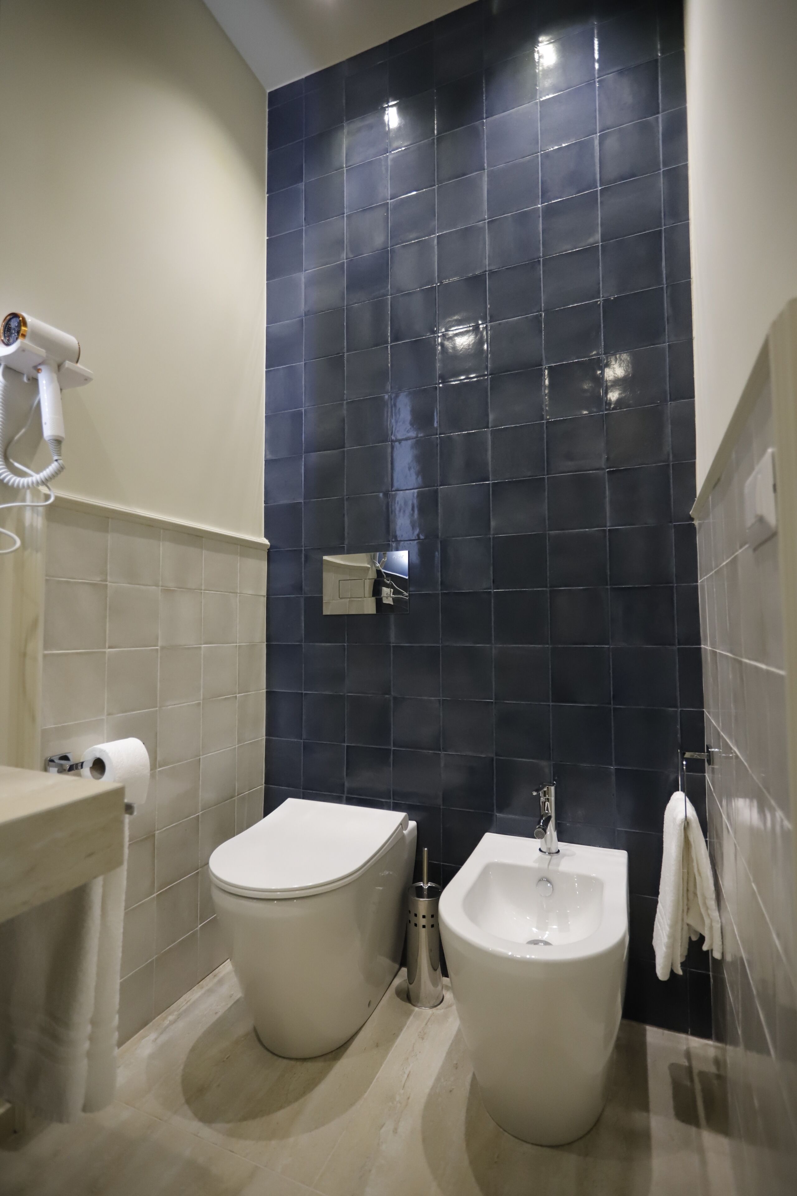 A bathroom with a toilet, bidet, and a hairdryer on a counter.