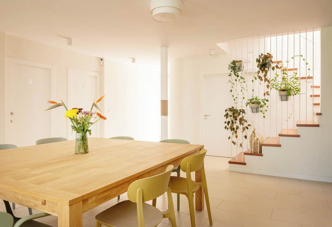 A modern dining area with a wooden table, yellow chairs, and a vase of flowers.