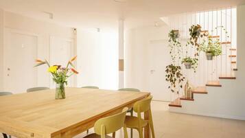 A modern dining area with a wooden table, yellow chairs, and a vase of flowers.