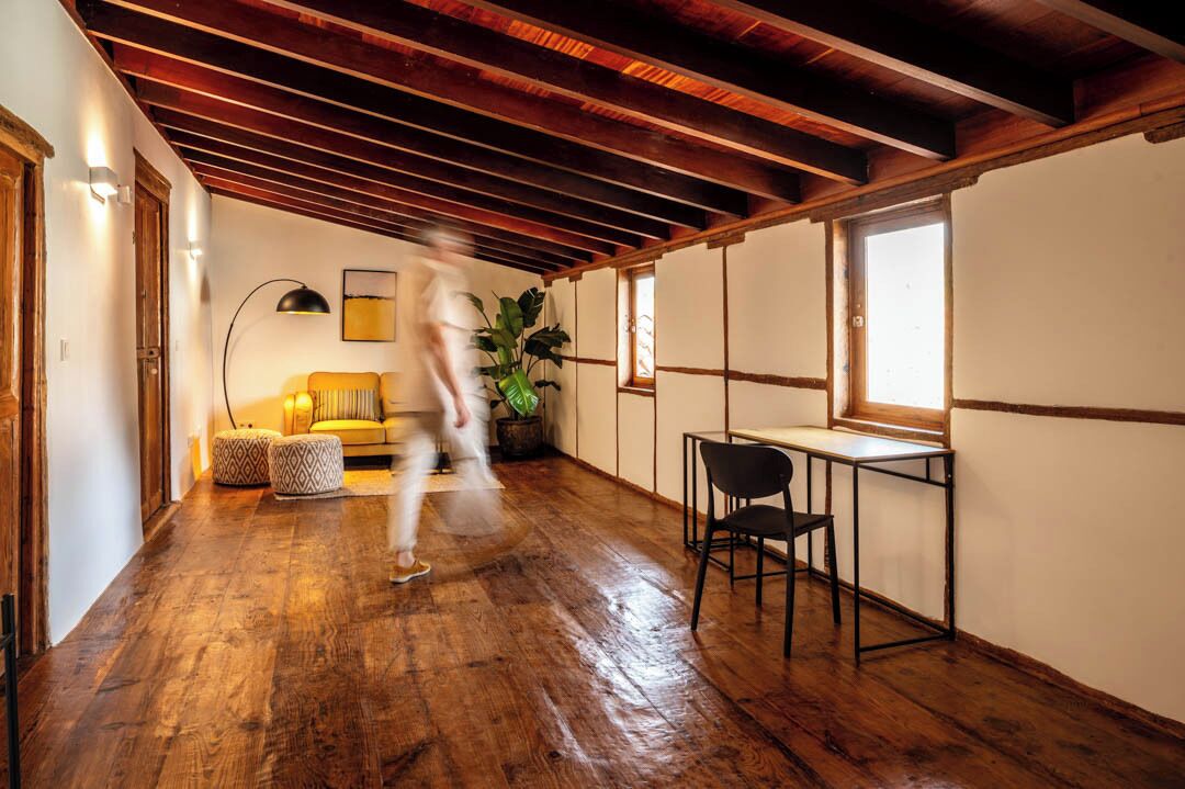 Een kamer met houten vloeren, een bank, een tafel en stoelen.