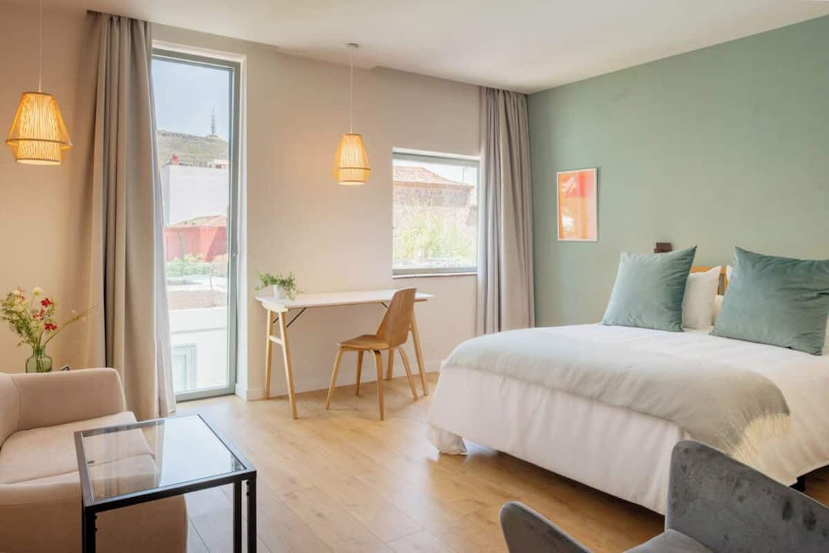 Una habitación de hotel moderna con cama, escritorio, silla y sofá.
