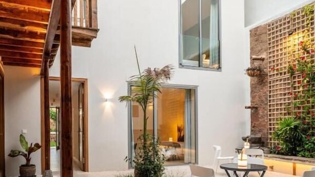 Une terrasse extérieure moderne, dotée d’une pergola en bois, d’un espace salon avec des chaises, une petite table et une plante en pot.