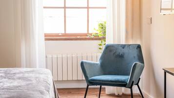 A room with a bed, a blue chair, a window with a view, and a radiator.