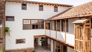 Un bâtiment à deux étages doté d’une cour intérieure, d’un balcon en bois et de plantes en pot.