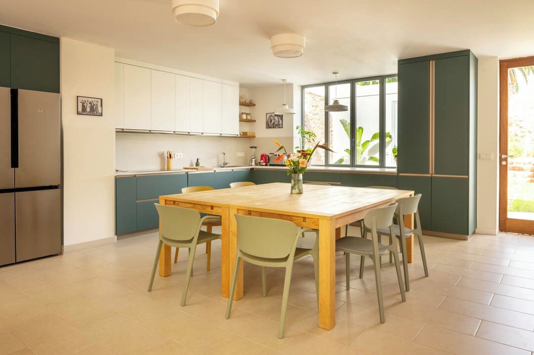 A modern kitchen with a dining table, chairs, and a refrigerator.