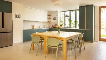 A modern kitchen with a dining table, chairs, and a refrigerator.