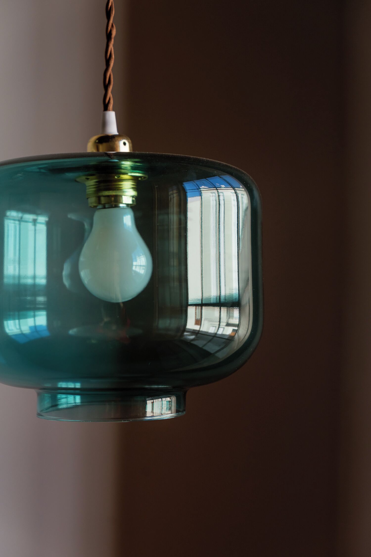 Un luminaire suspendu doté d’un abat-jour en verre et d’une ampoule visible.