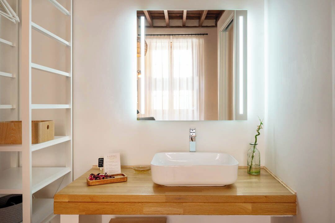 Une salle de bain avec un lavabo blanc, un meuble-lavabo en bois et un miroir au-dessus.