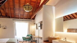 Une chambre à coucher comprenant un lit, une chaise, un bureau et une salle de bain avec un lavabo et un miroir.