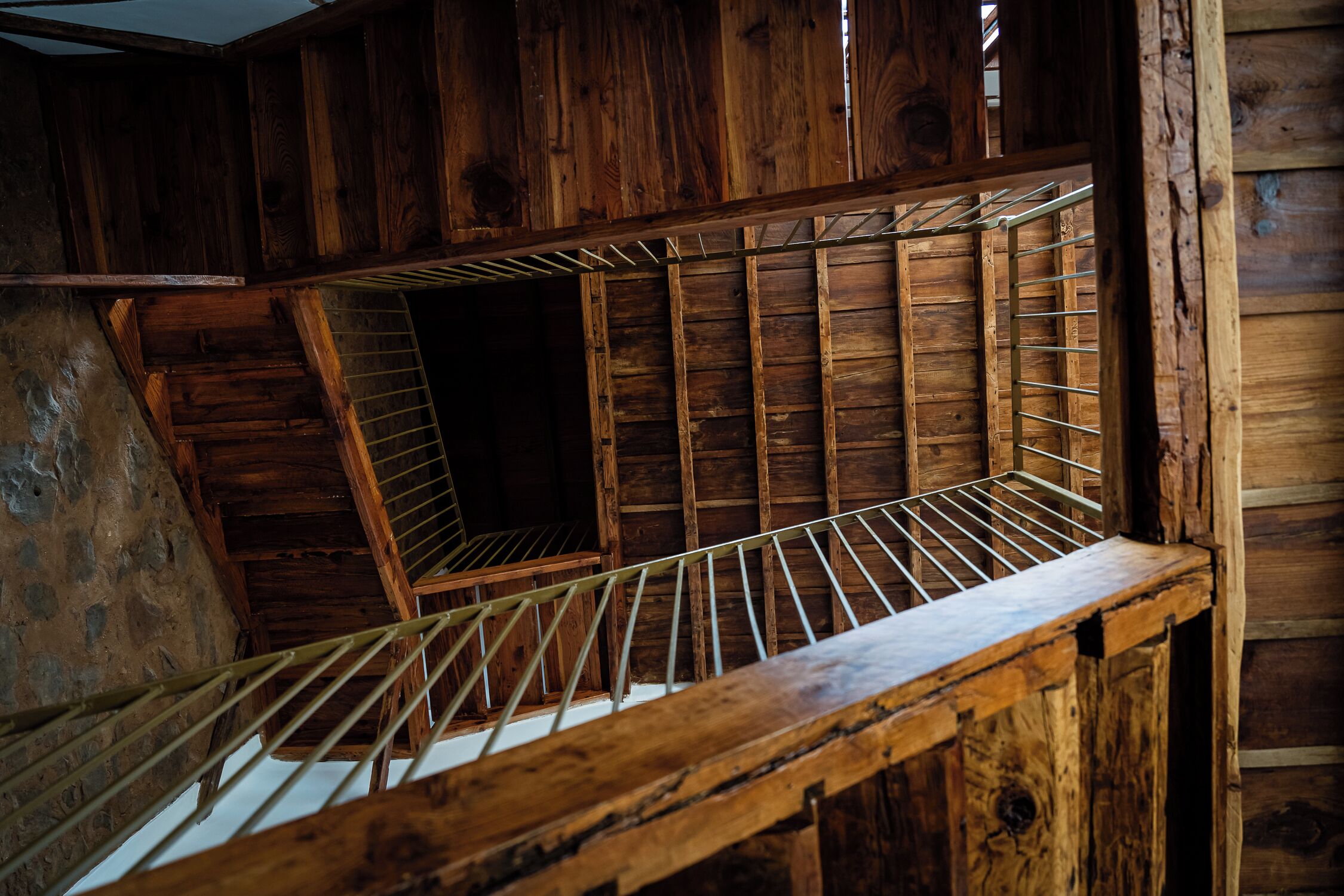 Un interno in legno con un soffitto spiovente, una rastrelliera metallica e una scala.