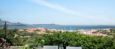 A table set for dining with a scenic view of the sea and buildings in the distance.