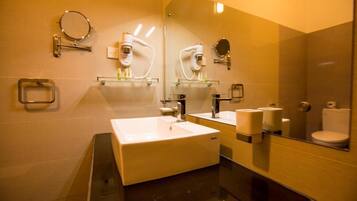A modern bathroom with a large mirror, two sinks, a toilet, and a hand dryer.
