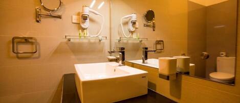A modern bathroom with a large mirror, two sinks, a toilet, and a hand dryer.