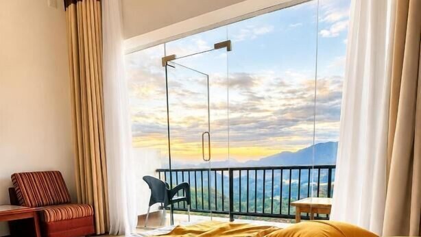 Habitación de hotel con cama, una silla, una mesa y un balcón con vistas.