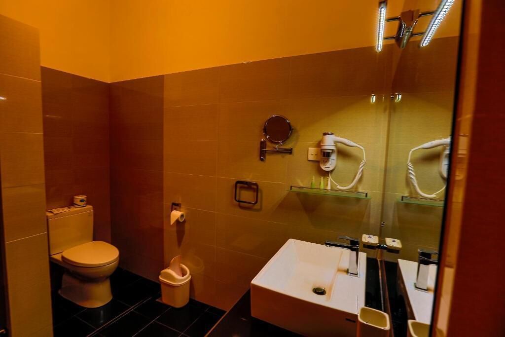 A bathroom with a toilet, sink, and mirror.