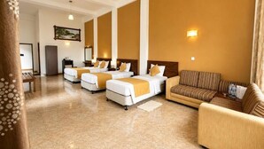 Habitación de hotel con cuatro camas, un sofá, un escritorio y un ventilador de techo.
