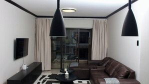 Una sala de estar moderna con un sofá, una mesa de centro, un televisor y lámparas colgantes.
