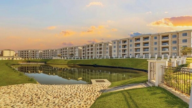 Un hotel moderno con piscina, césped verde y cielo despejado.