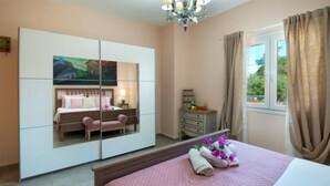 Une chambre à coucher comprenant un lit, une commode, un miroir, une table de chevet et une fenêtre avec des rideaux.