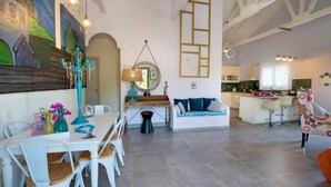 Un grand espace de vie comprenant une table à manger, des chaises, un canapé, une cuisine et un escalier.