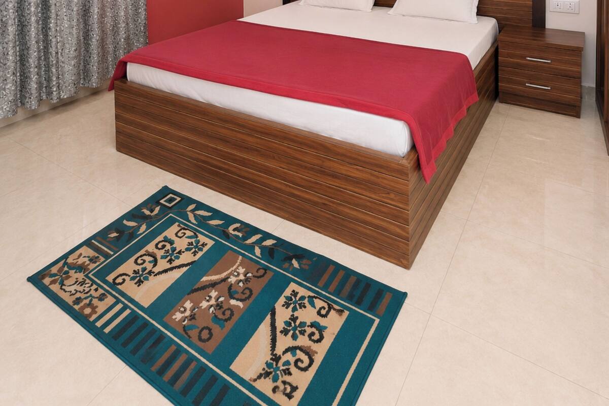 A bedroom with a wooden bed, a red wall, an air conditioning unit, a ceiling fan, and a patterned rug.