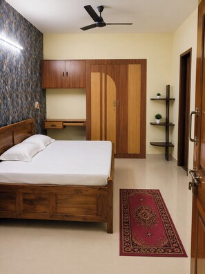 Un dormitorio con cama, armario, escritorio y ventilador de techo.