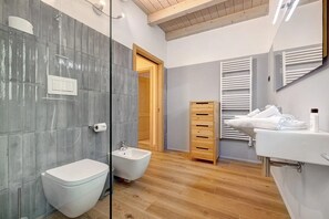 Une salle de bain moderne Ă©quipĂ©e dâun bidet, de toilettes et dâun lavabo.