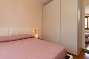 A bedroom with a bed, a bedside lamp, a wardrobe, and a mirror. - Casa Ald a Manna by Wonderful Italy (Olbia)
