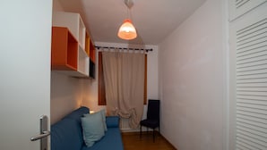 A room with a blue sofa, a chair, a hanging light fixture, and a door with a handle. - Casa Ald a Manna by Wonderful Italy (Olbia)