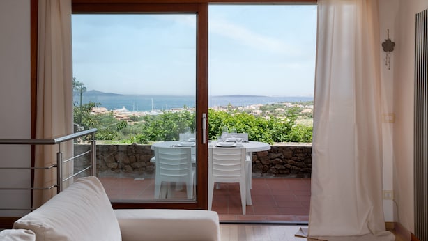 A balcony with a table and chairs, a view of the sea, and a stone wall. - Casa Ald a Manna by Wonderful Italy (Olbia)