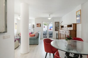 Ein modernes Wohnzimmer mit einer Couch, einem Esstisch mit Stühlen und einer Küchenzeile mit Schränken.