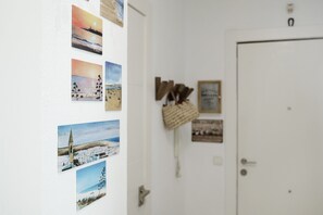 Ein Zimmer mit einer weißen Tür, einer Wand mit verschiedenen Fotos und einem kleinen Korb mit Gegenständen an der Wand.