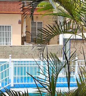 Ein Poolbereich mit einer Steinmauer, einem weißen Geländer und einem Stuhl.