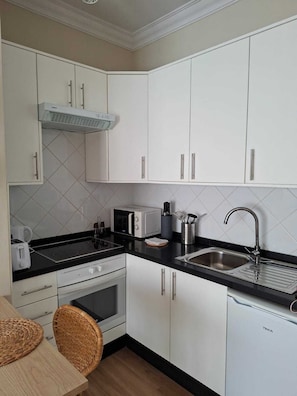 Eine moderne Küche mit weißen Schränken, einer schwarzen Arbeitsplatte, einem Backofen, einer Mikrowelle, einem Toaster und einem Spülbecken.