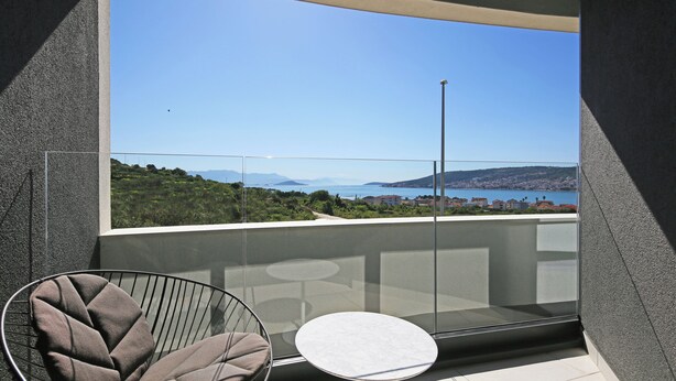 A balcony with a clear view of a coastal landscape, a round table, and a chair. - Trogir sky view suite (Trogir)