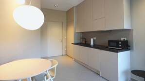 Una cocina moderna con una mesa redonda, sillas, un microondas y una lámpara colgante.