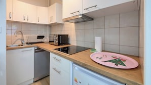 Cocina con armarios blancos, lavavajillas, microondas y un plato rosa con diseño navideño.